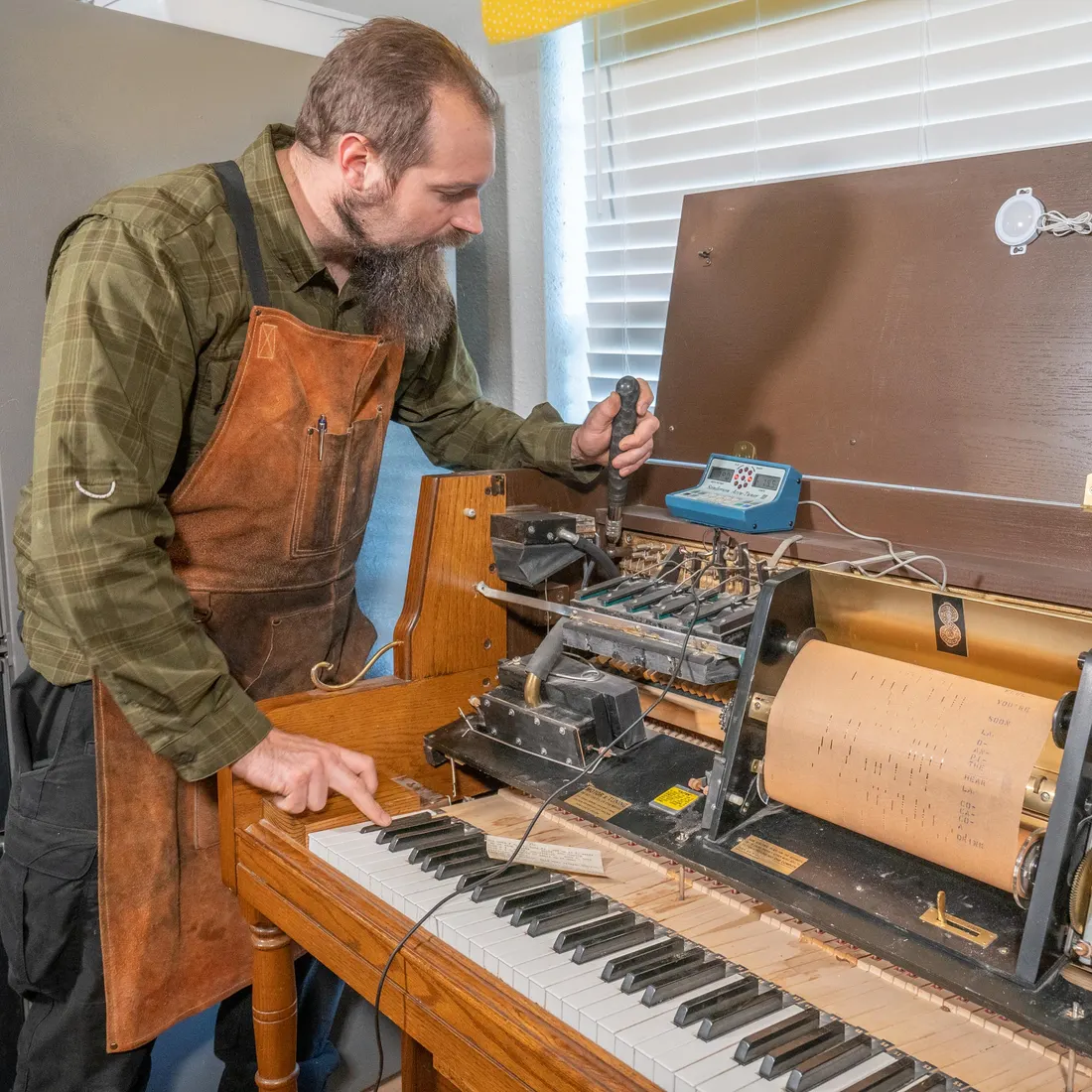 Justin Clare tuning a player piano in a home